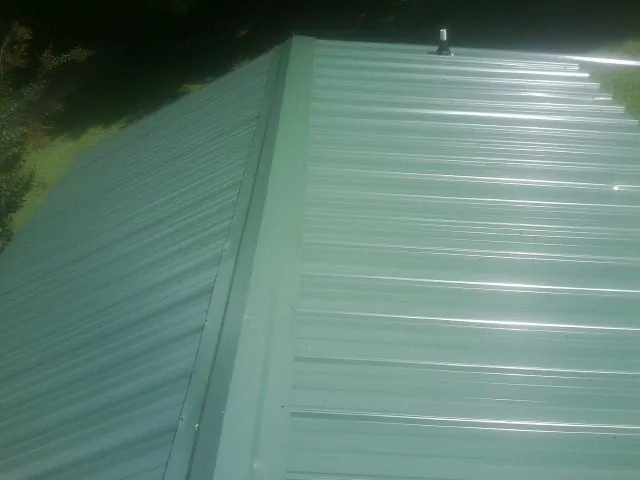 New green metal panels meeting at the ridge of a roof — Flat Roof Repair work by our crew in Stevensville