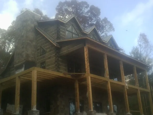 Stone chimney and dormers on a large log home with a timber porch in Stevensville